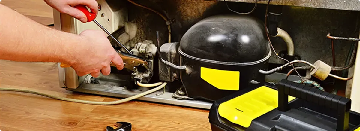 Refrigerator repair technician fixing the compressor and wiring in Orange, CT