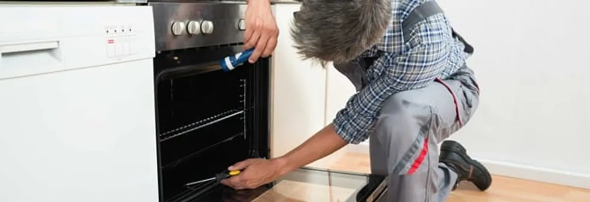 Oven repair technician inspecting and servicing an electric oven in New Haven, CT